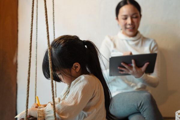 A child playing while the mother is using their tablet